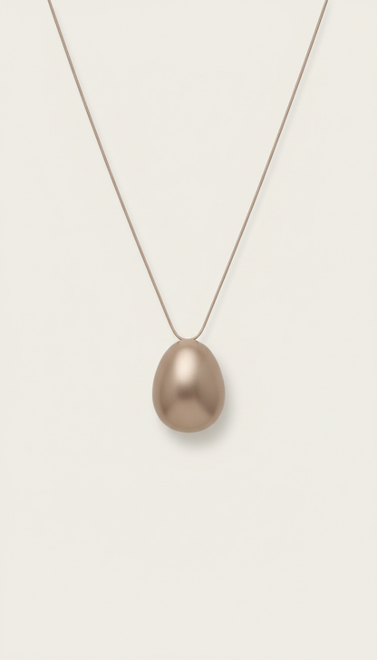 Minimalist Soft Taupe pendant necklace, Hero jewelry pieces captured at 3/4 angle on matte plinths or trays, allowing...