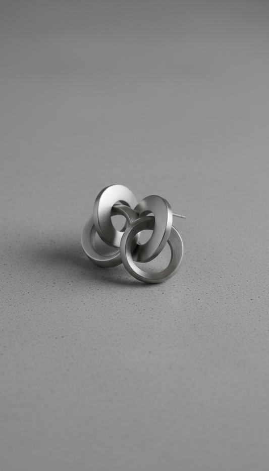 Capture contemporary stainless steel earrings in a 3/4 angle against a backdrop like matte concrete. The earrings are...